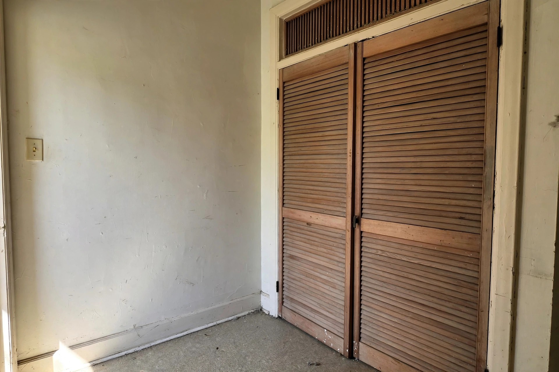 Louvred wooden doors closed over an apartment laundry closet in a hallway